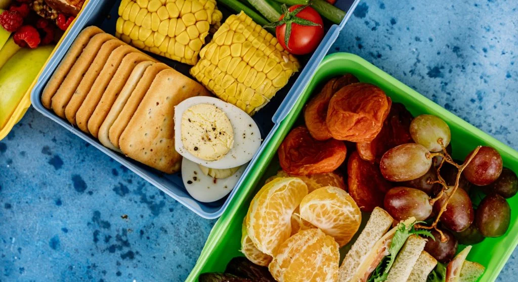 Boiled eggs, crackers, grapes, and vegetables in a travel lunch box